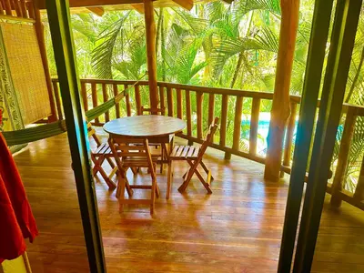 a table and chairs on a porch with palm trees at Pacifica Surf Studios in Santa Teresa Beach