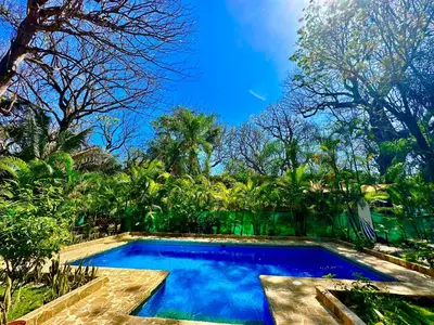 a swimming pool in the middle of a garden at Pacifica Surf Studios in Santa Teresa Beach