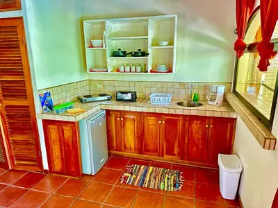 a small kitchen with wooden cabinets and a sink at Pacifica Surf Studios in Santa Teresa Beach