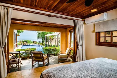 a bedroom with a bed and a patio with a pool at Exclusive Beachfront Villa Private Pool, Koi, BBQ in Tamarindo