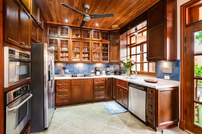 a kitchen with wooden cabinets and a ceiling fan at Relaxing Tropical Villa Near the Beach in Tamarindo