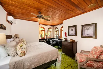 a bedroom with a bed with a ceiling fan and a desk at Relaxing Tropical Villa Near the Beach in Tamarindo