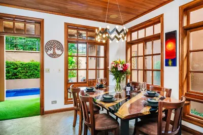 a dining room with a table and chairs and windows at Relaxing Tropical Villa Near the Beach in Tamarindo