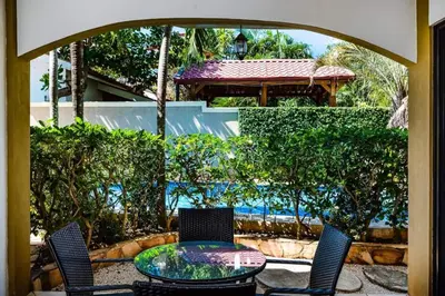 a patio with a glass table and chairs and a pavilion at Pool & AC Close to Beach with free bikes! in Tamarindo
