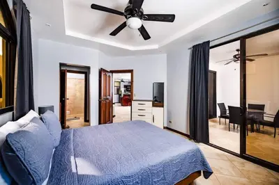 a bedroom with a blue bed and a ceiling fan at Pool & AC Close to Beach with free bikes! in Tamarindo