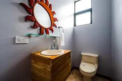 a bathroom with a sink and a mirror on the wall at Pool & AC Close to Beach with free bikes! in Tamarindo