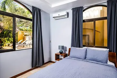 a bedroom with a bed and a large window at Pool & AC Close to Beach with free bikes! in Tamarindo