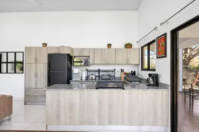 a kitchen with wooden cabinets and a counter top at Casa Las Mariposas Fantastic Home With Nature Views & Private Pool in Jobos