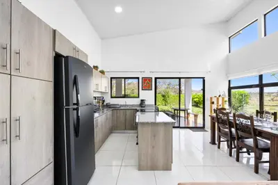 a kitchen with a stainless steel refrigerator and a table at Casa Las Mariposas Fantastic Home With Nature Views & Private Pool in Jobos