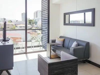 a living room with a couch and a large window at Urban Executive Stay in San José