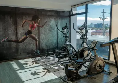 a woman running in a gym with two exercise bikes at Urban Executive Stay in San José
