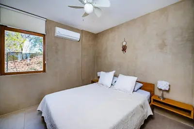 a bedroom with a white bed with a ceiling fan at Spacious & serene with partial ocean & jungle view in Tamarindo