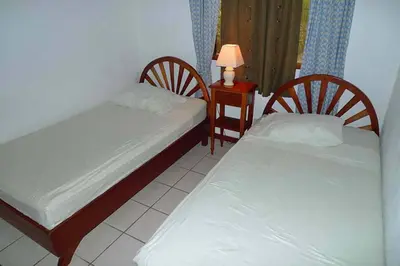 a bedroom with two beds and a table with a lamp at Centric, clean, safe, with pool & monkey visitors in Tamarindo