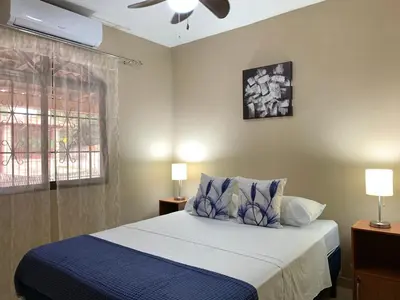 a bedroom with a bed and two lamps and a window at Posada Florencia AC near Guanacaste Airport in Liberia