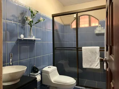 a blue tiled bathroom with a toilet and a sink at Posada Florencia AC near Guanacaste Airport in Liberia