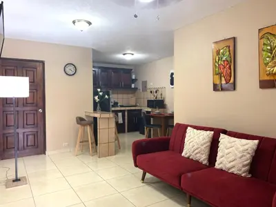 a living room with a red couch and a kitchen at Posada Florencia AC near Guanacaste Airport in Liberia