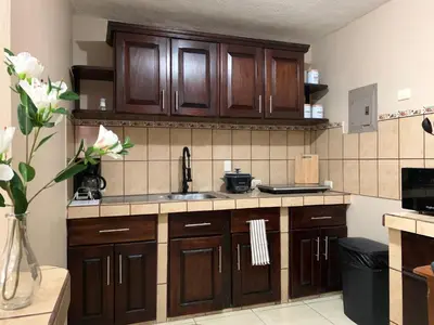 a kitchen with wooden cabinets and a sink at Posada Florencia AC near Guanacaste Airport in Liberia