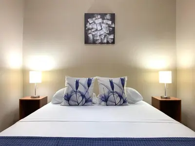 a bed with blue and white pillows and two lamps at Posada Florencia AC near Guanacaste Airport in Liberia