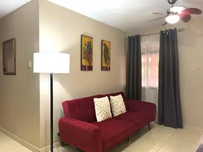 a red couch in a living room with a ceiling fan at Posada Florencia AC near Guanacaste Airport in Liberia
