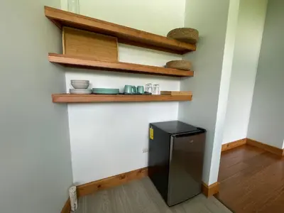 a kitchen with a black refrigerator and wooden shelves at Aires de Quetzales in Concepción