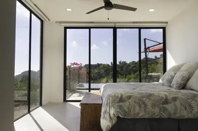 a bedroom with a bed and large glass windows at Prime Hermosa- Ocean View Villa with Infinity Pool in Playa Hermosa
