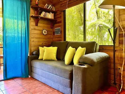 a couch with yellow pillows in a room with a window at Ocean Melody in Uvita