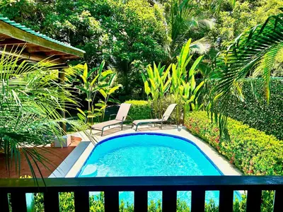 a small swimming pool with two chairs in a garden at Ocean Melody in Uvita