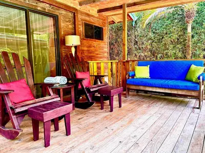 a porch with chairs and a blue couch on a deck at Ocean Melody in Uvita