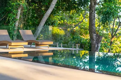 two chairs sitting on a deck next to a swimming pool at Casa Colibri - by Pura Villas in Uvita