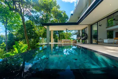 an infinity pool in the backyard of a house at Casa Colibri - by Pura Villas in Uvita