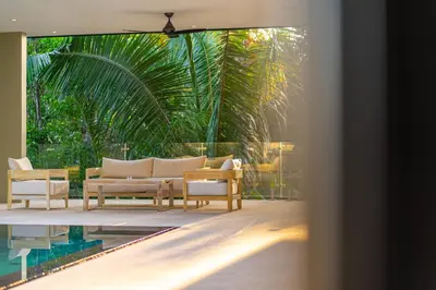 a living room with a couch and tables and a pool at Casa Colibri - by Pura Villas in Uvita