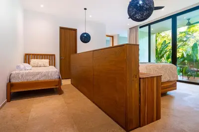 a bedroom with two beds and a large wooden cabinet at Casa Colibri - by Pura Villas in Uvita