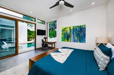 a bedroom with a blue bed and a ceiling fan at Private Pool with direct access to 2 beaches! in Tamarindo