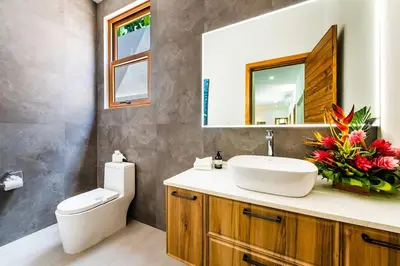 a bathroom with a sink and a toilet and a mirror at Private Pool with direct access to 2 beaches! in Tamarindo