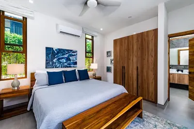 a bedroom with a large bed with blue pillows at Private Pool with direct access to 2 beaches! in Tamarindo