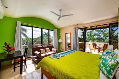 a green bedroom with a bed and a table and chairs at Private pool BBQ, Fast Wifi Alarm Close to Beach in Tamarindo