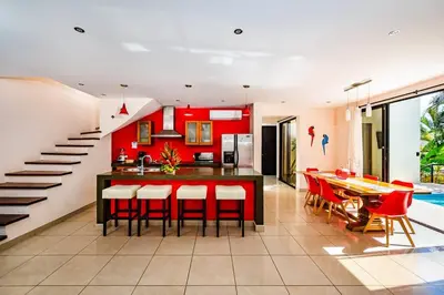 a kitchen and dining room with a red wall at Private pool BBQ, Fast Wifi Alarm Close to Beach in Tamarindo