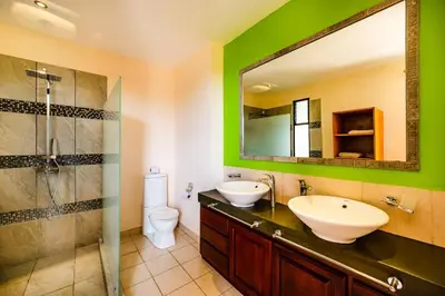 a bathroom with a sink and a toilet and a mirror at Private pool BBQ, Fast Wifi Alarm Close to Beach in Tamarindo