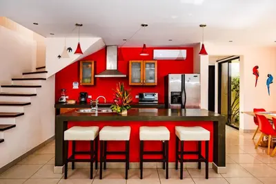 a kitchen with red walls and a island with bar stools at Private pool BBQ, Fast Wifi Alarm Close to Beach in Tamarindo