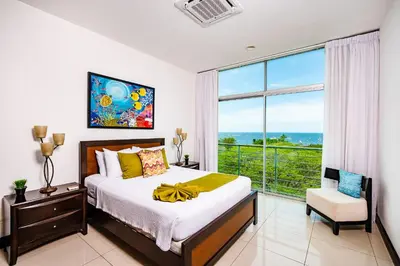 a bedroom with a large bed and a large window at Pura Vida Penthouse w ocean and sunset views in Tamarindo