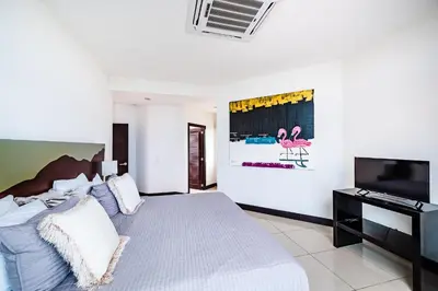 a bedroom with a bed and a flat screen tv at Pura Vida Penthouse w ocean and sunset views in Tamarindo