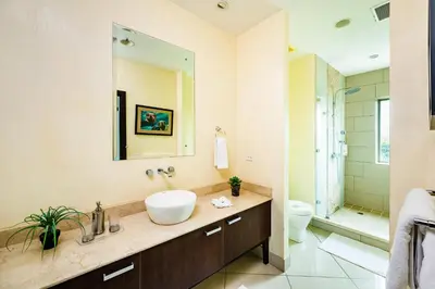 a bathroom with a sink and a toilet and a mirror at Pura Vida Penthouse w ocean and sunset views in Tamarindo