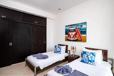 a bedroom with two beds and a painting on the wall at Pura Vida Penthouse w ocean and sunset views in Tamarindo