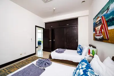 a bedroom with two beds and a painting on the wall at Pura Vida Penthouse w ocean and sunset views in Tamarindo