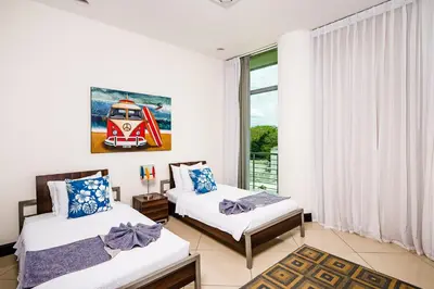 two beds in a room with a window at Pura Vida Penthouse w ocean and sunset views in Tamarindo