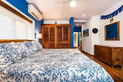 a bedroom with a large bed and a wooden dresser at Light & Breezy Beach Side Condo! in Tamarindo