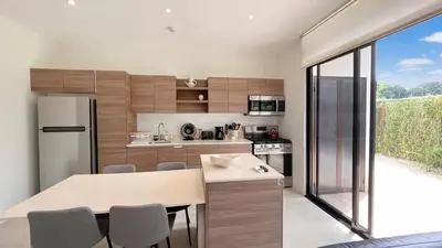 a kitchen with a refrigerator and a table with chairs at Exclusive fully equipped Condo with great pool in Jacó