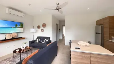 a living room with a blue couch and a tv at Exclusive fully equipped Condo with great pool in Jacó