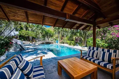 a patio with chairs and a swimming pool at Newly Remodeled Villa Across from the beach in Tamarindo