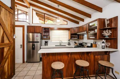 a kitchen with wooden cabinets and a sink and stools at Newly Remodeled Villa Across from the beach in Tamarindo